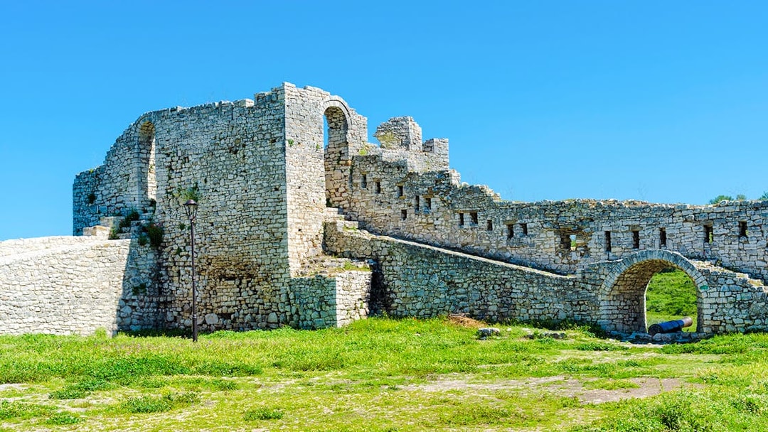 Berat Castle stone walls and archway under a clear blue sky in Albania.