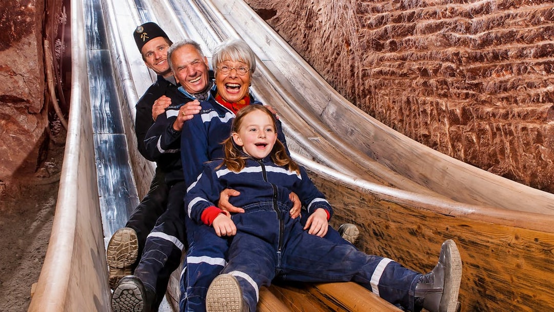 Visitors sliding down wooden chute in Bavarian salt mine, Berchtesgaden tour from Salzburg.