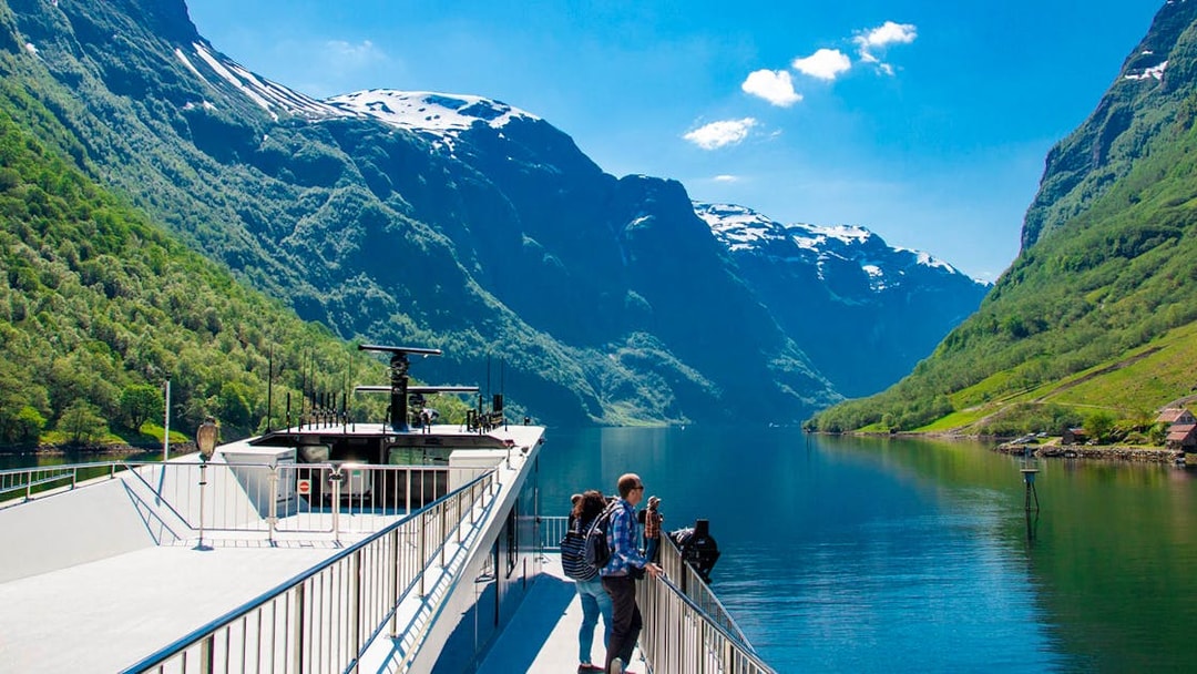 Cruise ship on Nærøyfjord with passengers enjoying scenic mountain views, Norway.