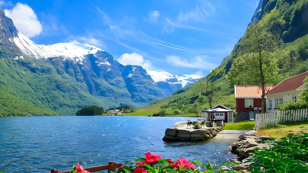 Nærøyfjord with snow-capped mountains, red-roofed house, and vibrant flowers in Norway.