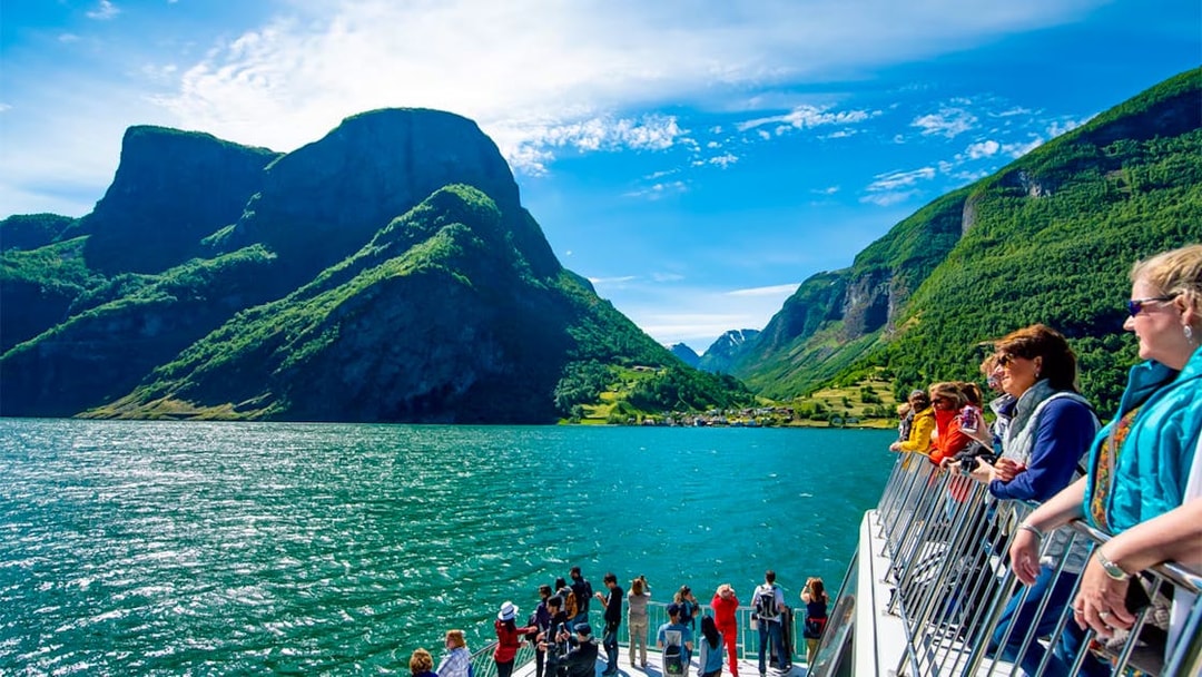 Tourists on a cruise ship deck enjoying views of Nærøyfjord's mountains and water.