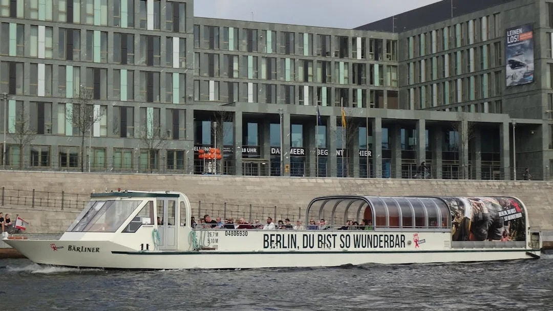 Sightseeing cruise boat on the River Spree in Berlin passing modern buildings.