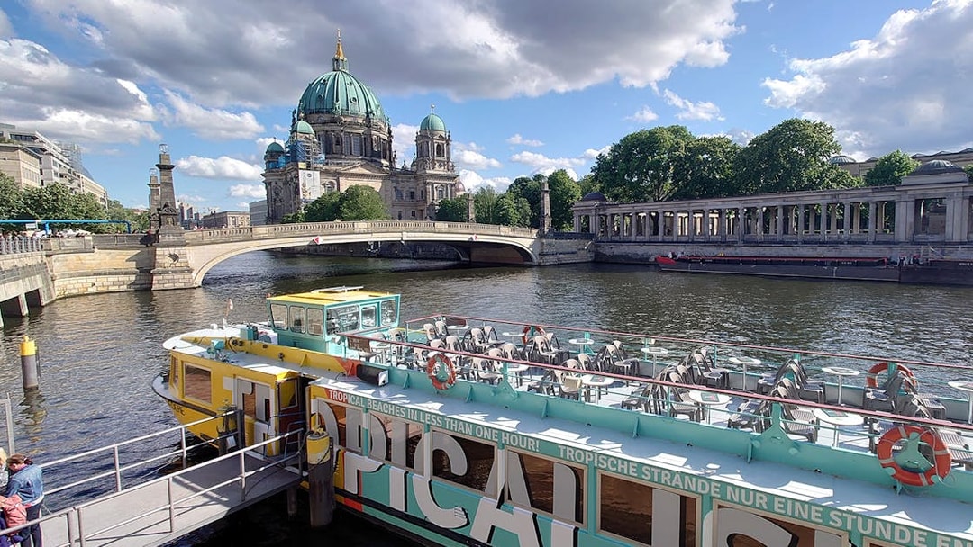 Sightseeing cruise boat on the River Spree with Berlin Cathedral in the background.