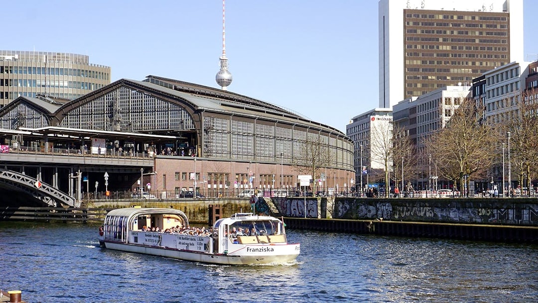 River cruise boat with tour guide passing Berlin's Friedrichstraße station.