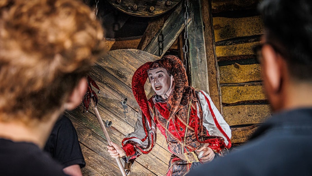 Jester performing at the Berlin Dungeon with audience in foreground.