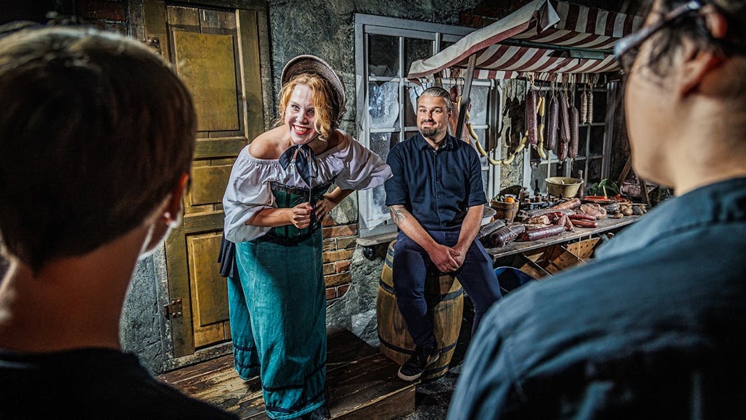 Tour guide in historical costume engaging visitors inside Berlin Dungeon.