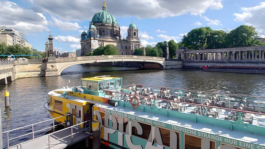 Sightseeing cruise boat on the Spree River with Berlin Cathedral in the background.
