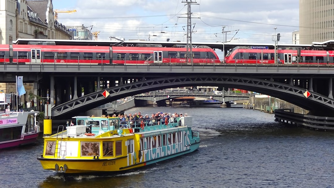 Sightseeing cruise boat on the Spree River in East Berlin passing under a railway bridge.