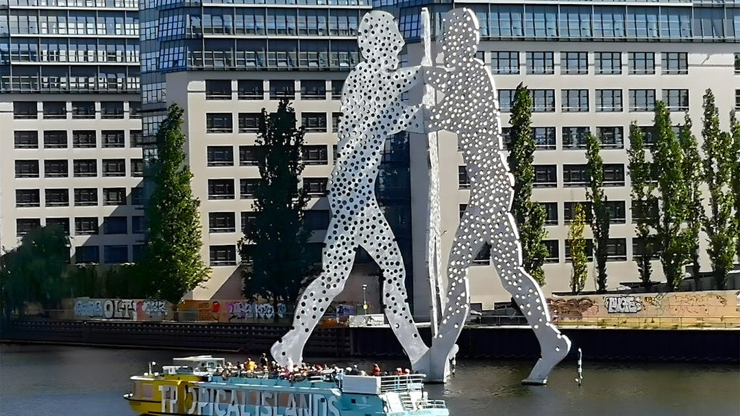 Sightseeing cruise passing the Molecule Man sculpture on the Spree River in East Berlin.