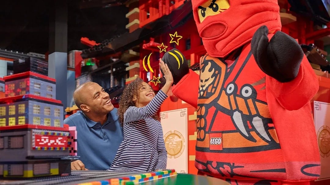 Child high-fiving LEGO character at LEGOLAND Discovery Centre Berlin entrance.