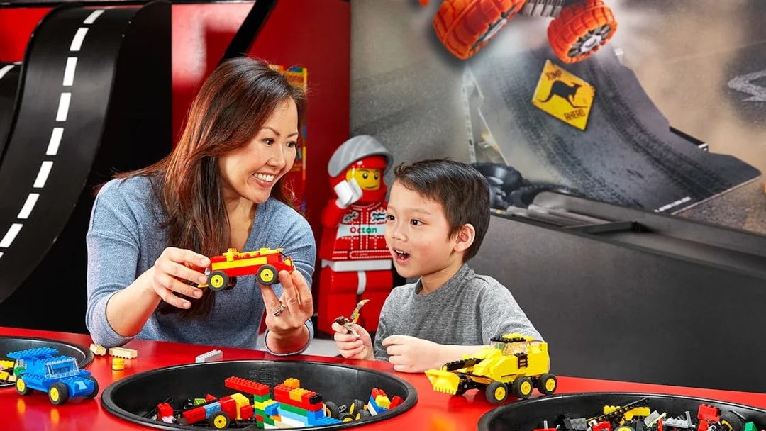 Child and adult building LEGO cars at indoor playground, LEGOLAND Discovery Centre Berlin.