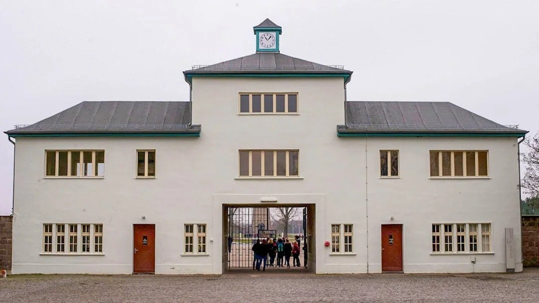 Main entrance of Sachsenhausen Concentration Camp with visitors entering through the gate.