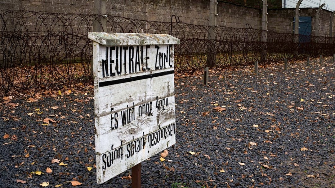 Barbed wire fence and warning sign at Sachsenhausen Concentration Camp, Germany.