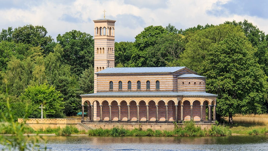 Church of the Redeemer by the water at Sacrow port, surrounded by trees.
