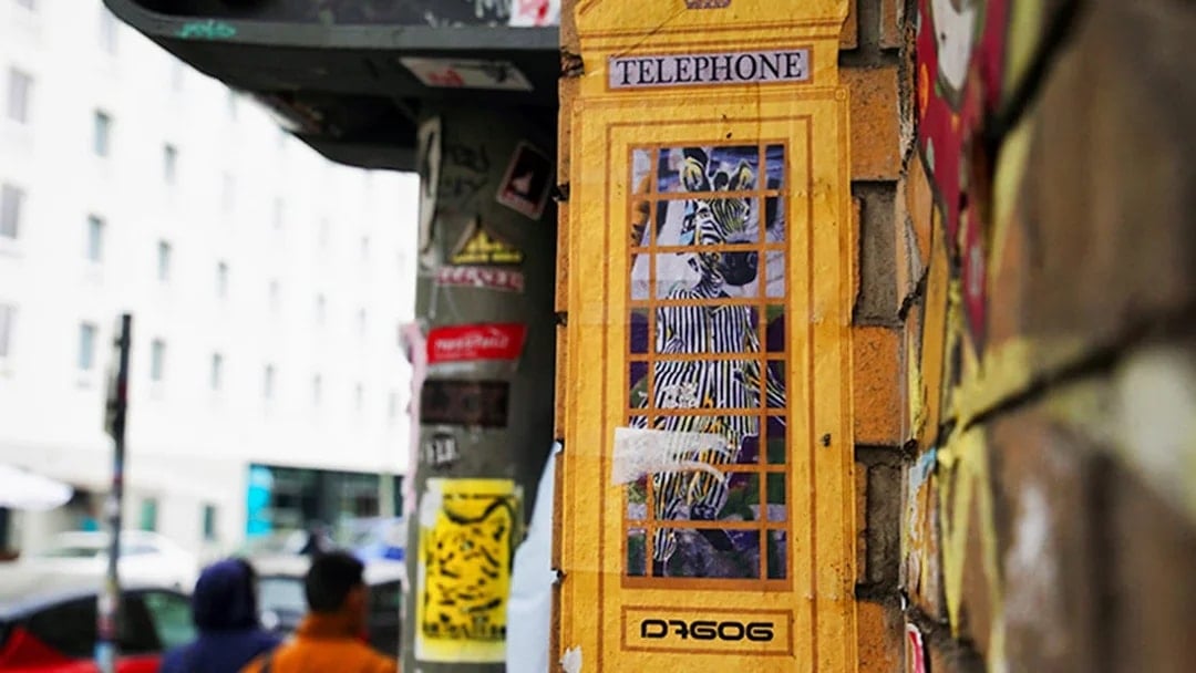 Street art of a zebra in a yellow phone booth on a Berlin wall during a guided tour.