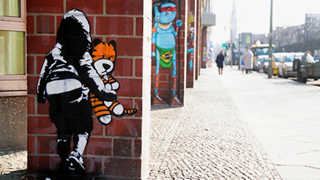 Street art on a Berlin wall featuring a child with a stuffed tiger during a guided tour.