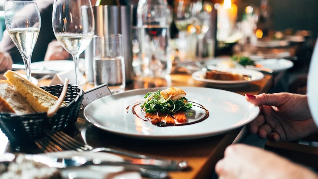 Fine dining experience at Berlin TV Tower with gourmet dish and wine glasses.