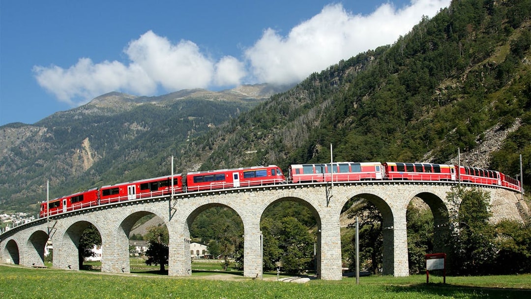 Bernina Express crossing a stone viaduct in the Swiss Alps.