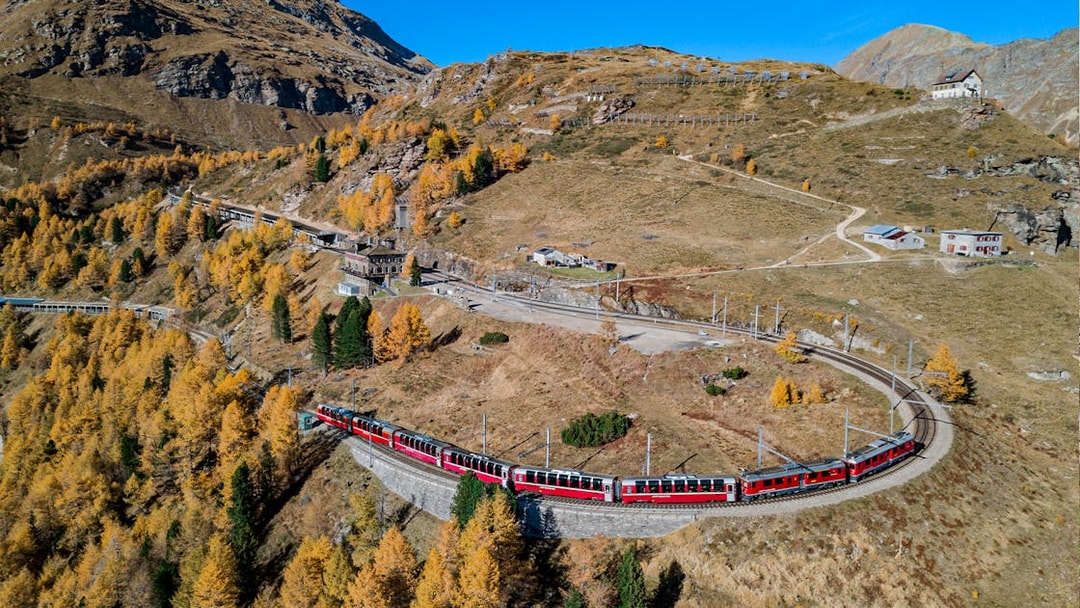 Bernina Express train winding through autumnal Swiss Alps towards Tirano.