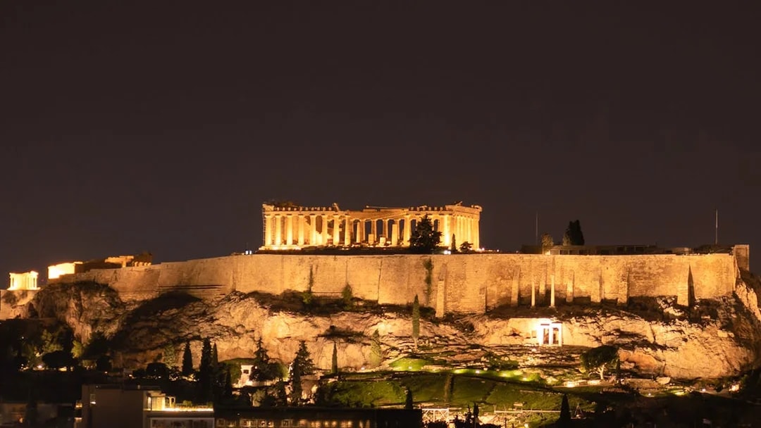 Acropolis illuminated at night on a hill in Athens, Greece.