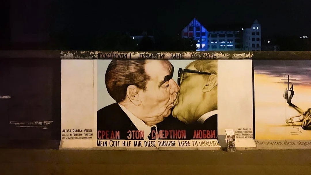 Berlin Wall mural at night featuring a famous political artwork.