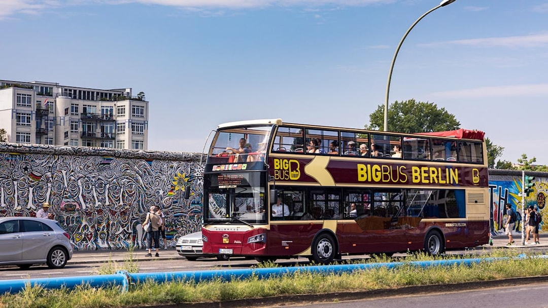 Big Bus Berlin tour passing by the Berlin Wall with colorful murals.