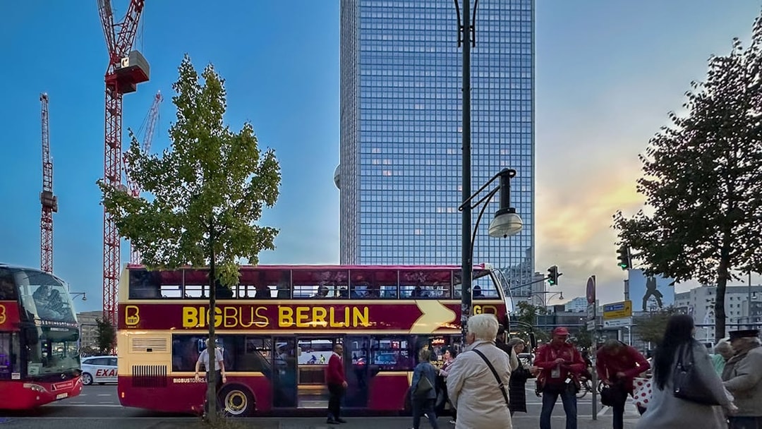 Berlin double-decker bus tour with cityscape and cranes in the background.