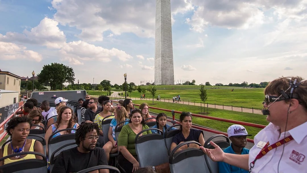 Tourists on a Big Bus Tour in Washington, D.C., with the Washington Monument in the background.