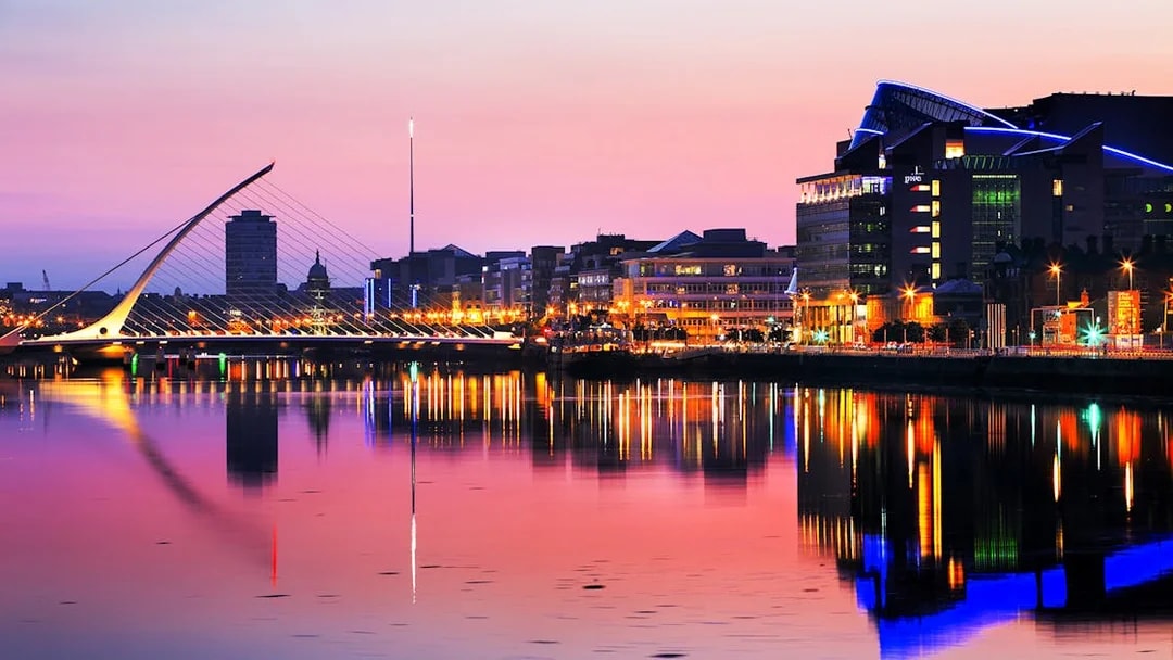 Samuel Beckett Bridge and Dublin skyline at sunset, reflecting on the River Liffey.