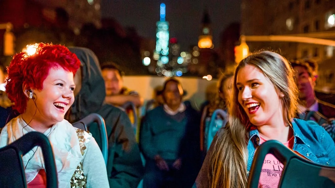 Two women enjoying a Dublin night tour on an open-top bus.