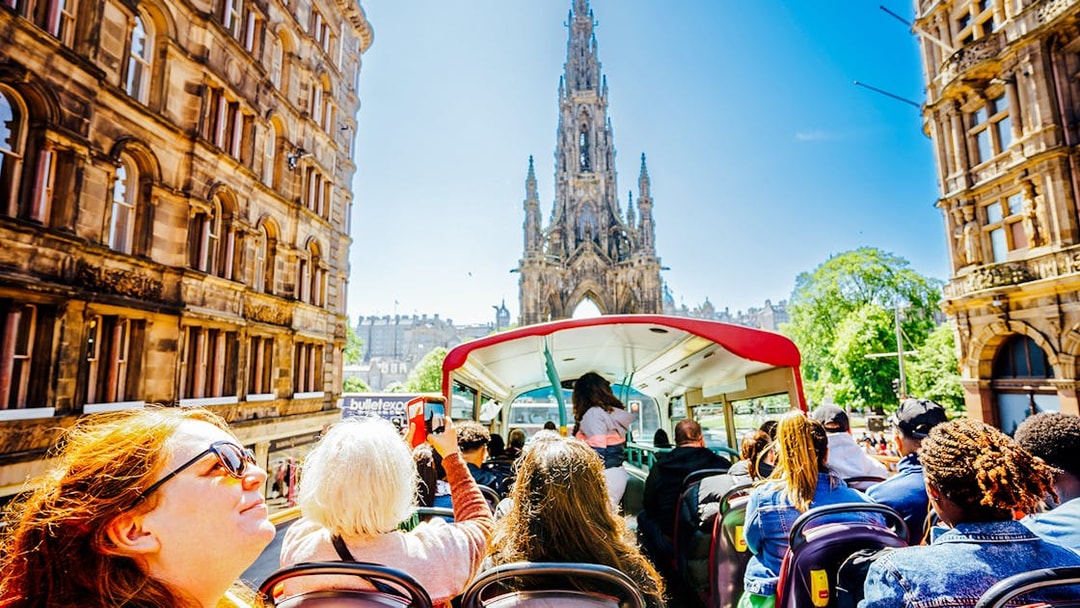 Open-top bus tour passing the Scott Monument in Edinburgh.
