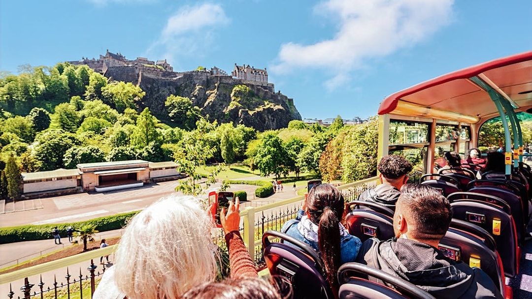 Open-top bus tour with view of Edinburgh Castle in the background.