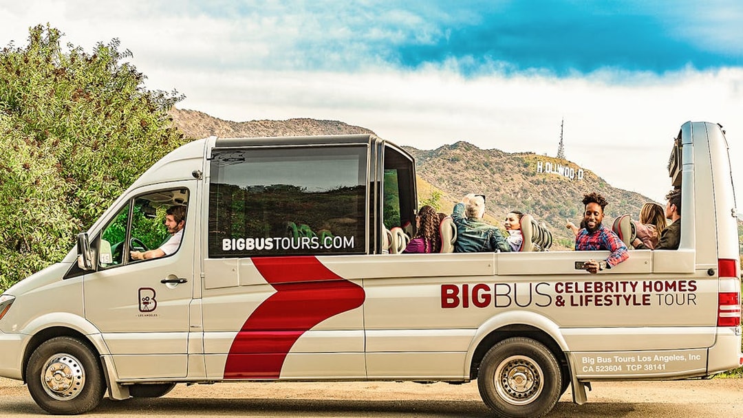 Open-top bus on Celebrity Homes Tour with Hollywood Sign in Los Angeles.