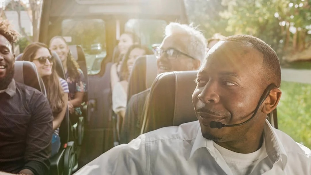 Tour guide leading a group on a Celebrity Homes Tour bus.