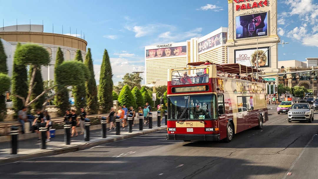 Open-top bus on Las Vegas Strip near Caesars Palace during Big Bus Hop On Hop Off tour.