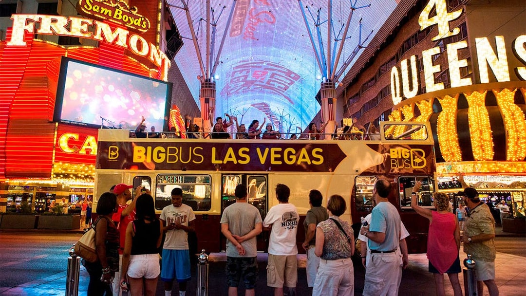 Big Bus tour in Las Vegas at night on Fremont Street with illuminated signs.