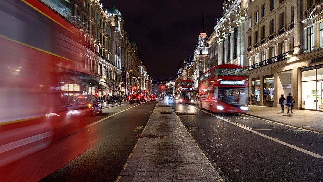 Red double-decker buses on a busy London street at night during the Big Bus Panoramic Evening Tour.