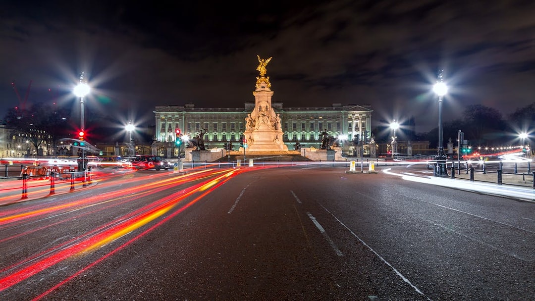 Buckingham Palace illuminated at night with light trails from passing traffic.