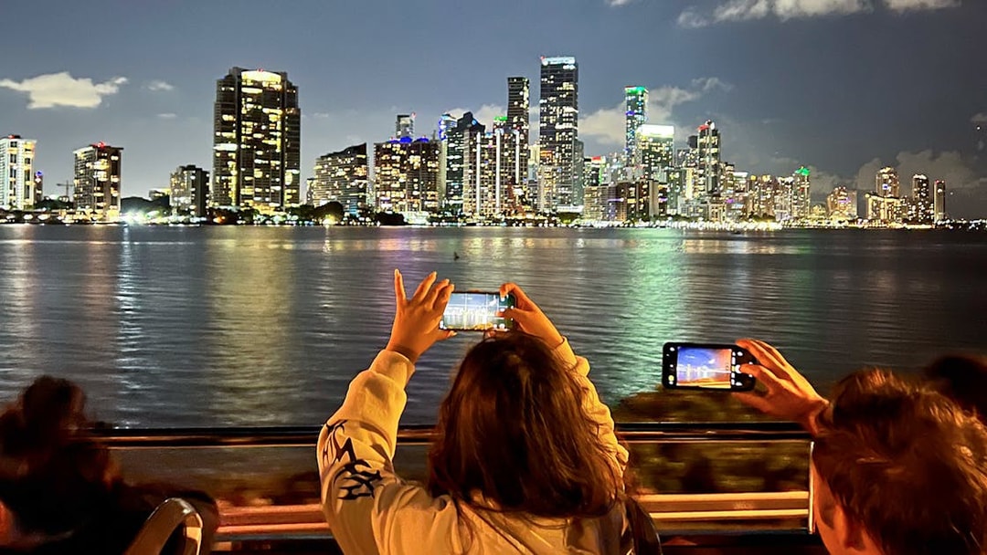 Passengers capturing Miami's illuminated skyline from the Big Bus Miami Panoramic Night Tour.