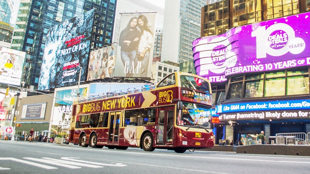 Big Bus tour passing through Times Square, New York City, with bright billboards.