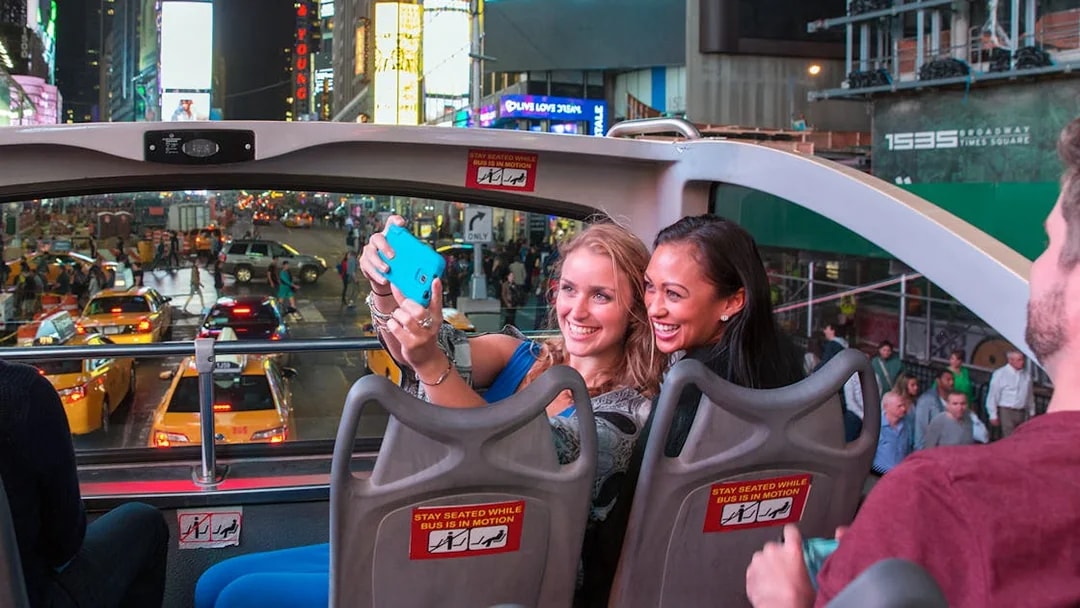 Passengers taking a selfie on a Big Bus night tour in Times Square, New York City.