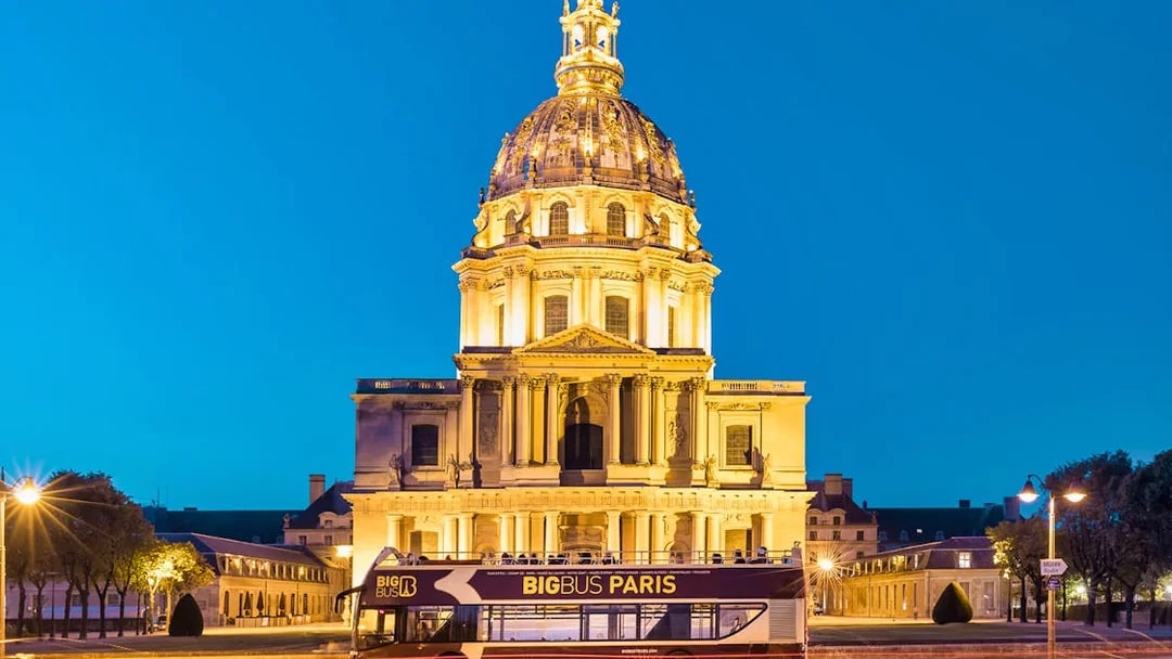 Big Bus tour passing Les Invalides at night in Paris.