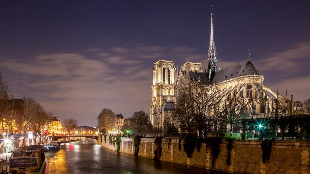 Notre-Dame Cathedral illuminated at night along the Seine River, Paris.