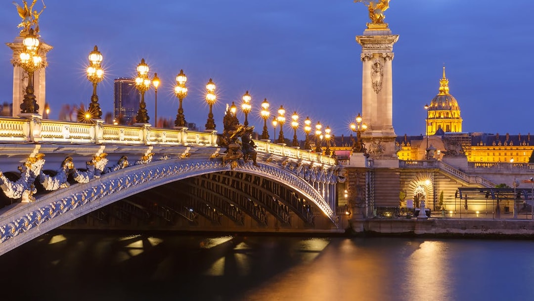 Night view of Pont Alexandre III and Les Invalides along the Seine in Paris, France.