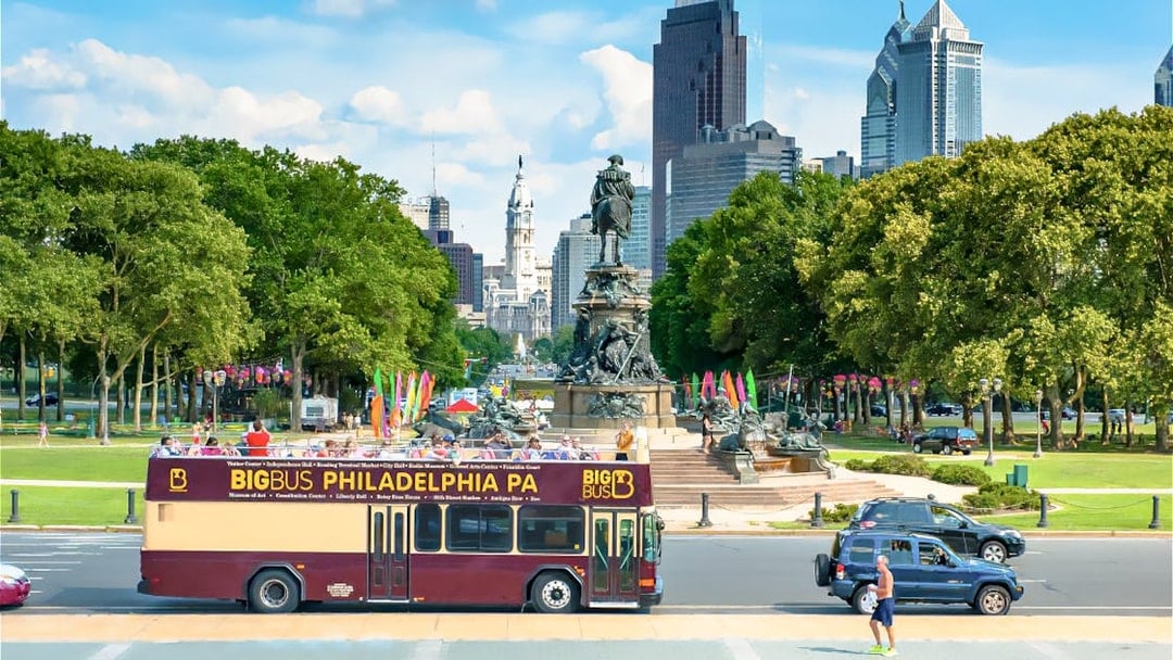 Big Bus tour in Philadelphia passing by the Benjamin Franklin Parkway with city skyline.