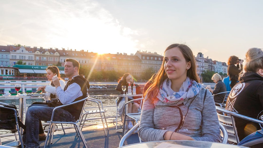 Woman enjoying a sunset cruise on the Vltava River in Prague.
