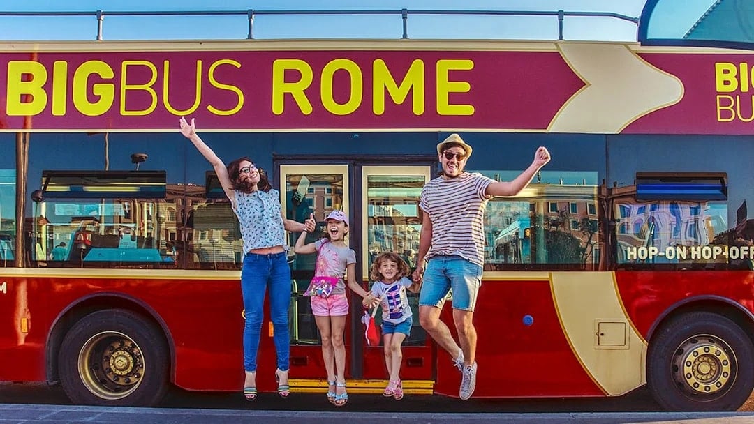Family jumping in front of Big Bus Rome, excited for city tour.