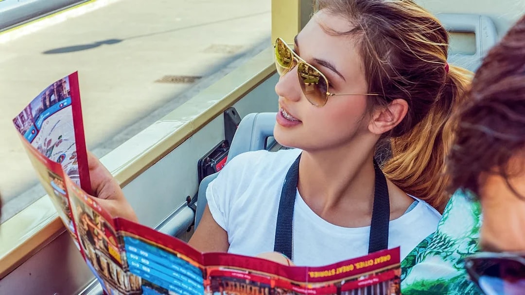 Woman examining Big Bus tour map on an open-top bus.