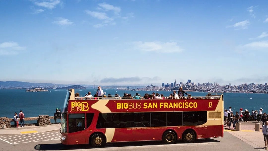 Big Bus San Francisco at viewpoint with city skyline and bay in background.