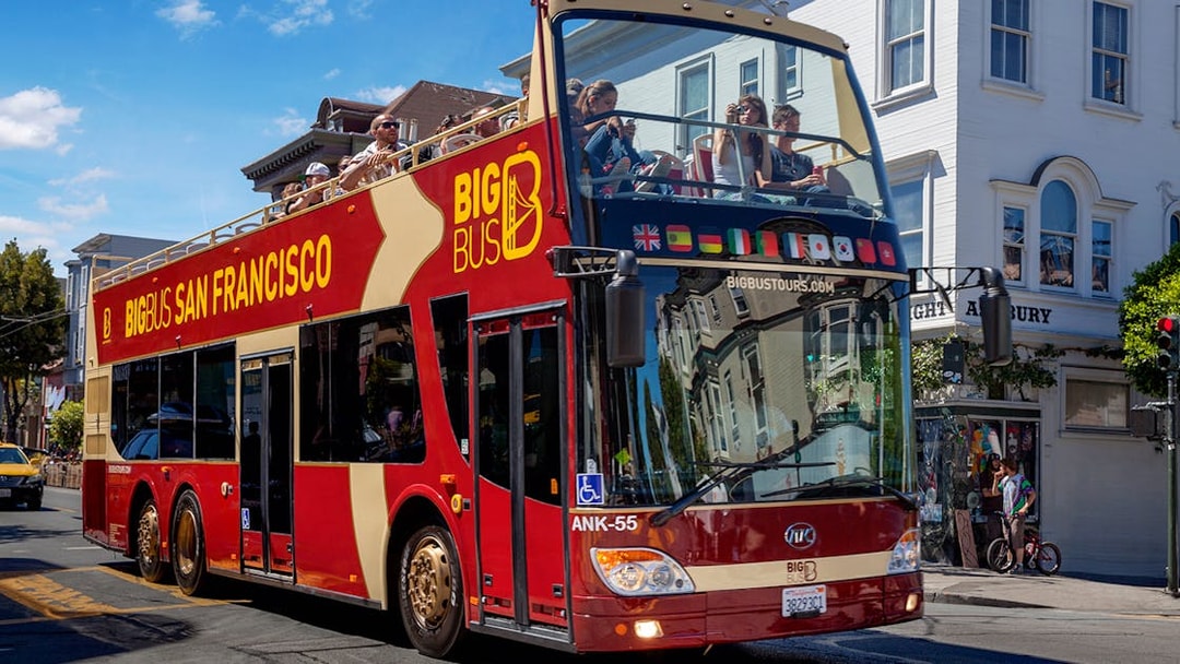 Open-top Big Bus tour in San Francisco passing through a city street.
